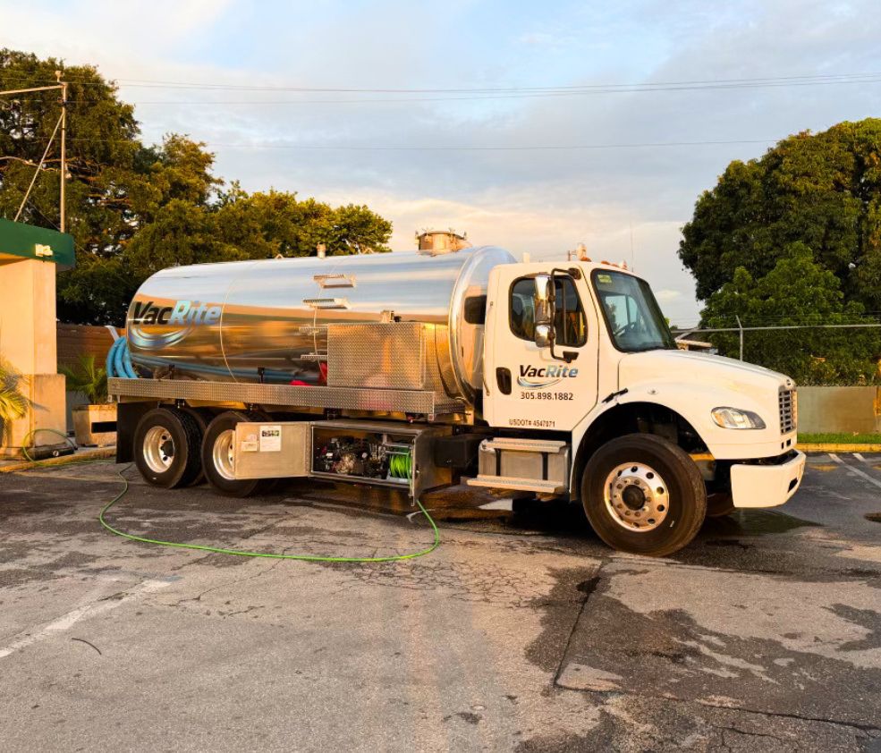 A VacRite tanker truck at golden hour with its suction hose run out across the pavement